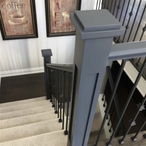 shaker stair newel post with black metal spindles on a staircase